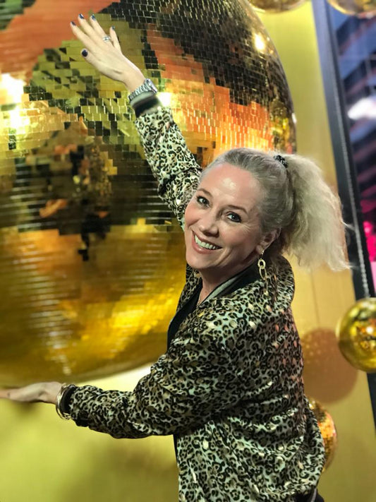 Andrea Quast, Goldschmiedemeisterin und Gründerin von Goldie Things, lachend vor einer Discokugel - 25 Jahre handgemachten Schmuck mit Herz.